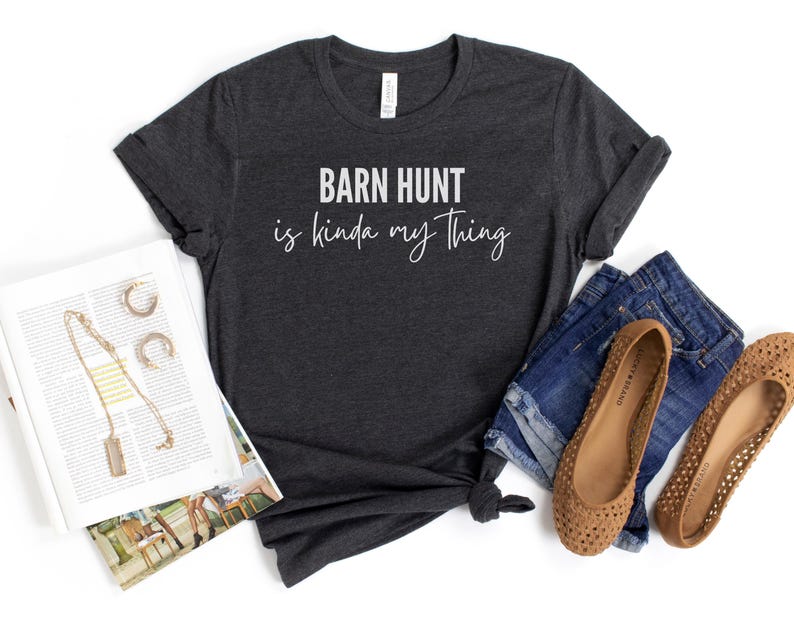 May include: Dark gray t-shirt with the text "Barn Hunt is kinda my thing" in white lettering.