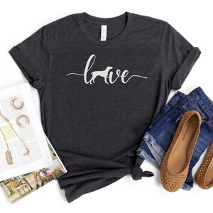 May include: A dark gray t-shirt with the word "love" written in white with a silhouette of a dog in the "o".