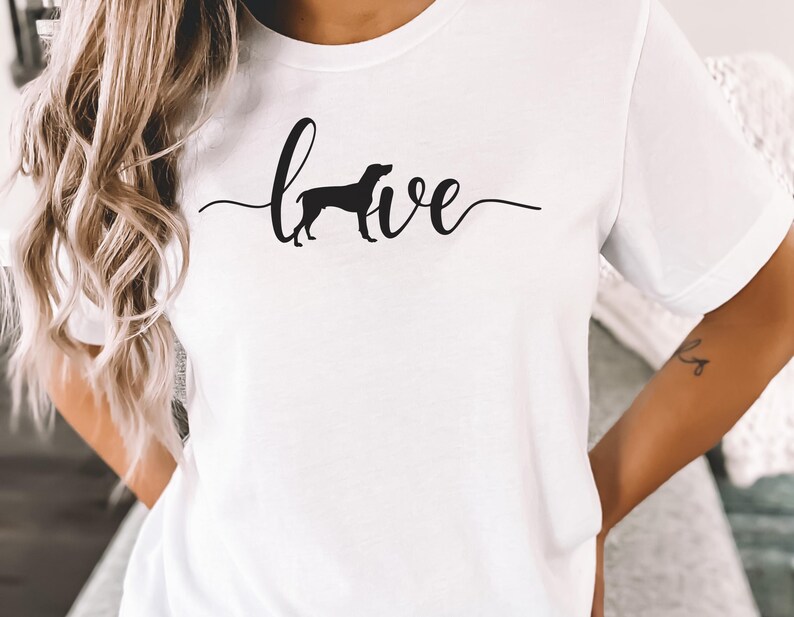 May include: White t-shirt with a black silhouette of a dog and the word "love" written in cursive.