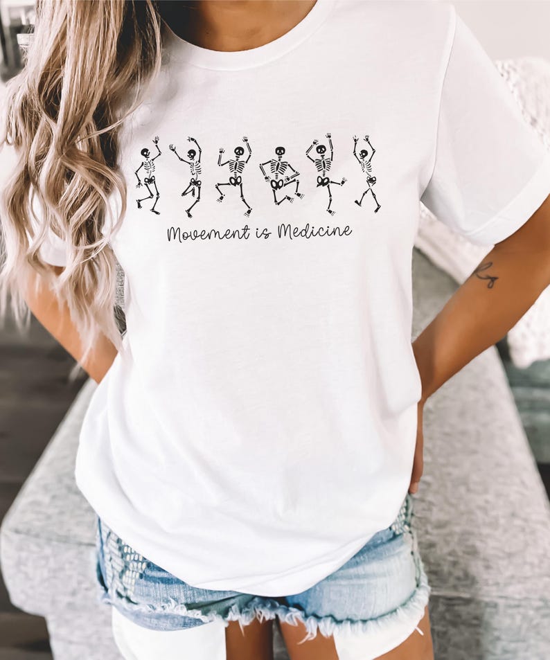 K&ouml;nnte beinhalten: Wei&szlig;es T-Shirt mit einer Grafik von tanzenden Skeletten und dem Text "Bewegung ist Medizin".