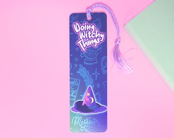 May include: A blue and purple bookmark with a witch hat design and the text "Doing Witchy Things". The bookmark has a purple tassel.
