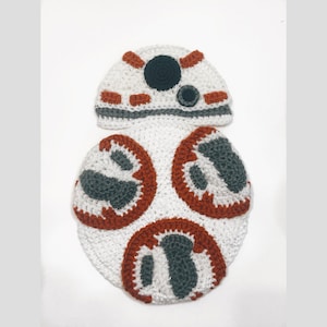 May include: A handmade crochet outfit resembling the Star Wars character BB-8. The set includes a white hat with orange and black details, and a matching white body with orange and gray accents. The outfit is designed for a baby or toddler.