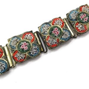 May include: Vintage floral mosaic bracelet with a silver-tone metal frame. The bracelet features colorful mosaic tiles in red, blue, and green, with a central flower design in each panel. The bracelet is approximately 7 inches long.