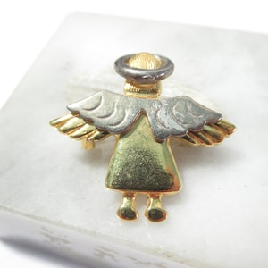 May include: A gold and silver angel pin with wings and a halo. The angel is wearing a gold dress and has a silver halo.