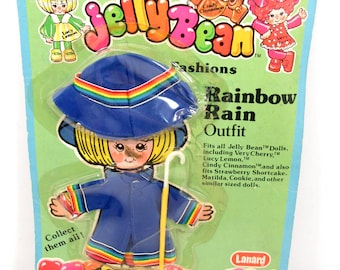 Puede incluir: Un conjunto de accesorios de muñeca Rainbow Rain Outfit de Jelly Bean Fashions vintage. El conjunto incluye un sombrero de lluvia azul con borde arcoíris, un impermeable azul con ribete arcoíris y un bastón amarillo. El embalaje presenta personajes de dibujos animados.