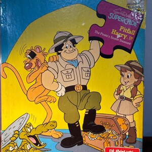 May include: Vintage Playskool jigsaw puzzle box featuring the cartoon characters from "Pitfall Harry in The Pirate's Secret Treasure." The box art shows a treasure chest, a cartoon crocodile, and other characters. The puzzle is for ages 3 to 6.