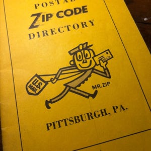 May include: A vintage yellow Postal Zip Code Directory. The cover features the text "Postal Zip Code Directory" and an illustration of "Mr. Zip" delivering mail. The directory is for Pittsburgh, PA.