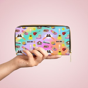 May include: A pink, blue, and yellow zippered wallet with a repeating pattern of images from the movie Back to the Future. The images include the DeLorean time machine, a clock tower, a skateboard, a milkshake, and a pair of Doc Brown's shoes.