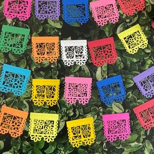 May include: A set of 16 colorful paper banners with intricate cut-out designs featuring flowers and a window-like shape. The banners are strung together and are perfect for a festive celebration.