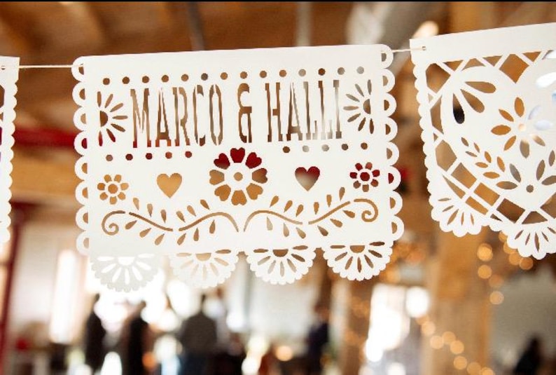 May include: White paper banner with a cut-out design, featuring the text "Marco & Hall" in a decorative font.