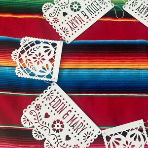 May include: White paper cut-out banner with the words "EDIN & MARY" and "NOW & NIGHT" on a colorful striped background.