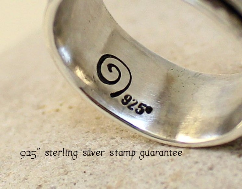 May include: Close-up of a silver ring with a swirl design and the marking "925" on the inside band.