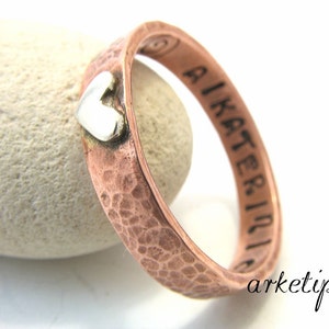 Peut inclure: Une bague en cuivre martelé avec un petit charme en forme de cœur en argent et l'inscription "AIKATERINI" sur la bande.