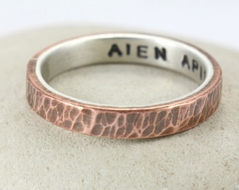 May include: A hammered copper band ring with a silver interior. The inscription "AIEN API" is engraved on the inside of the ring.