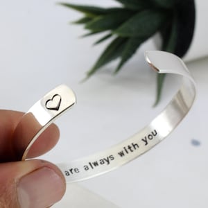 Könnte beinhalten: Silbernes Armreif-Armband mit der Gravur "are always with you" auf der Außenseite und einem kleinen Herz auf der Innenseite.