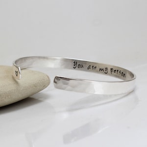 Könnte beinhalten: Ein silbernes, gehämmertes Armkettchen mit der Inschrift "You are my person" und einem kleinen Herz auf der Innenseite.