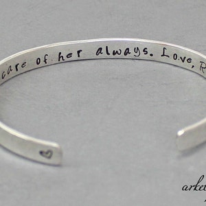 Op de afbeelding: Zilveren armband met de inscriptie "Zorg altijd goed voor haar. Liefs, Ryan" en een klein hartje gegraveerd aan de binnenkant.