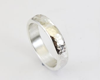 May include: A silver hammered band ring. The ring is smooth on the inside and has a hammered texture on the outside.
