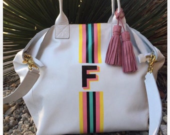 Mini Noha Tote en blanco piel brillante con rayas centrales en amarillo, rosa, negro y aqua con inicial grande en negro con doble sombra