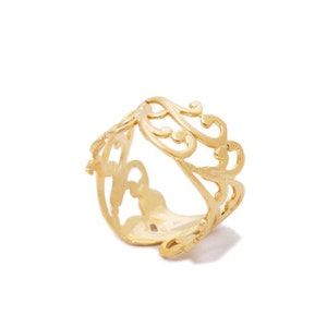 May include: A gold filigree ring with a delicate, intricate design. The ring is made of a thin metal and has a wide band.