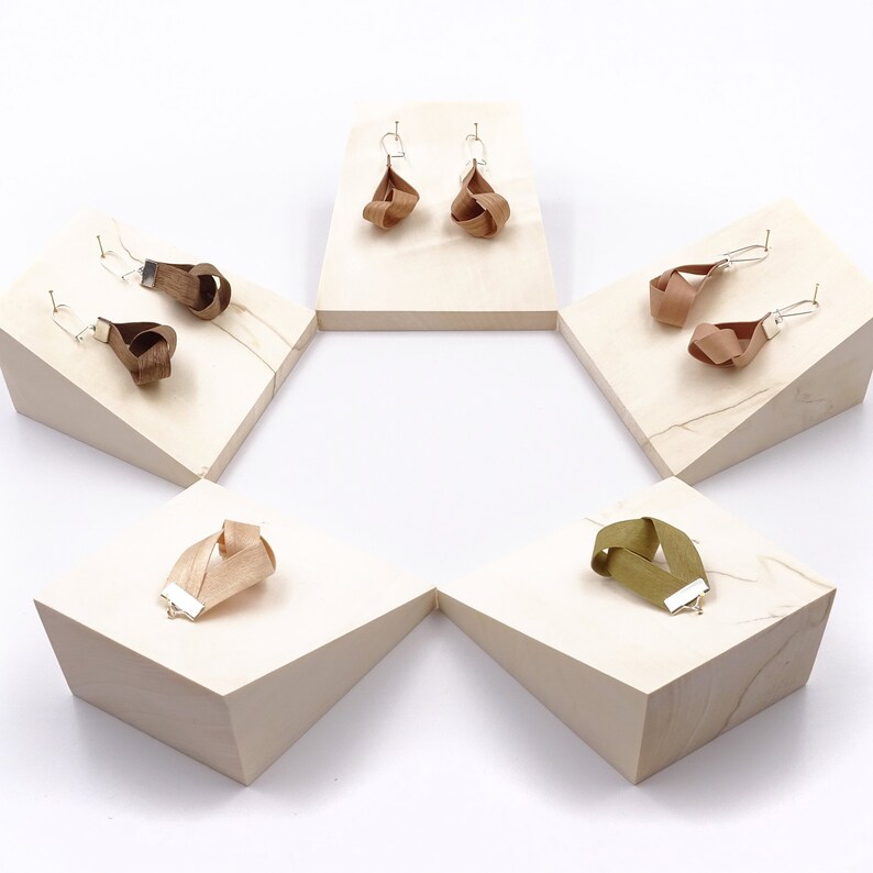 May include: Five wooden display stands with different colored fabric earrings and bracelets. The stands are arranged in a hexagon shape.