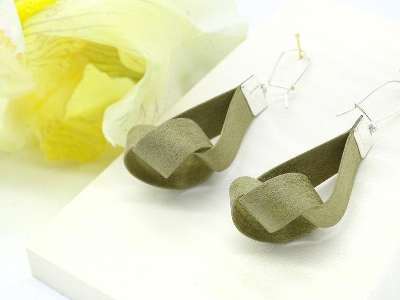 May include: A pair of olive green knotted fabric earrings with silver hooks.