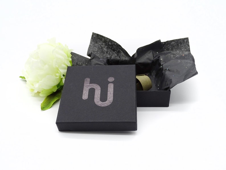 May include: A black gift box with the word "hi" printed in silver on the top. The box is open and filled with black tissue paper.