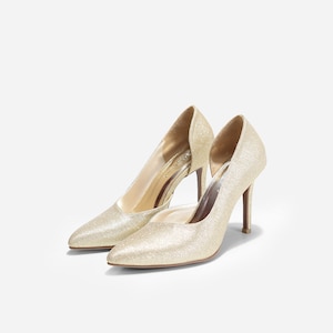 May include: A pair of gold glitter high heels with a pointed toe and a stiletto heel.
