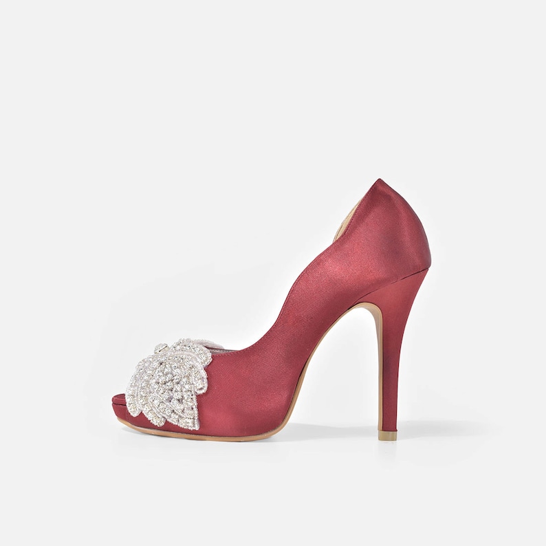 May include: Burgundy satin peep-toe heels with a jeweled embellishment on the toe.