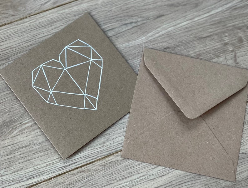 May include: A brown card with a white geometric heart design and a matching brown envelope.