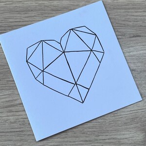 May include: A white card with a black geometric heart design.