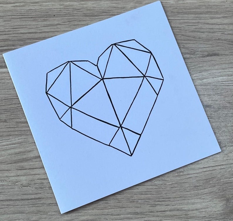 May include: A white card with a black geometric heart design.