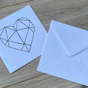 May include: A white card with a black geometric heart design. The card is accompanied by a white envelope.