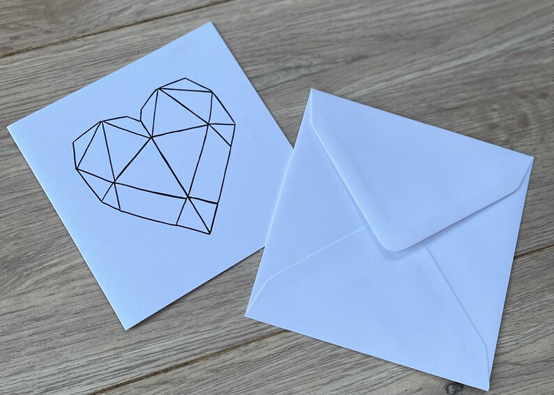 May include: A white card with a black geometric heart design. The card is accompanied by a white envelope.