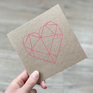 May include: A brown card with a pink geometric heart design.