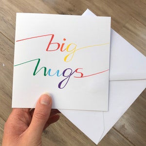 May include: A white card with the words "big hugs" written in rainbow colors.