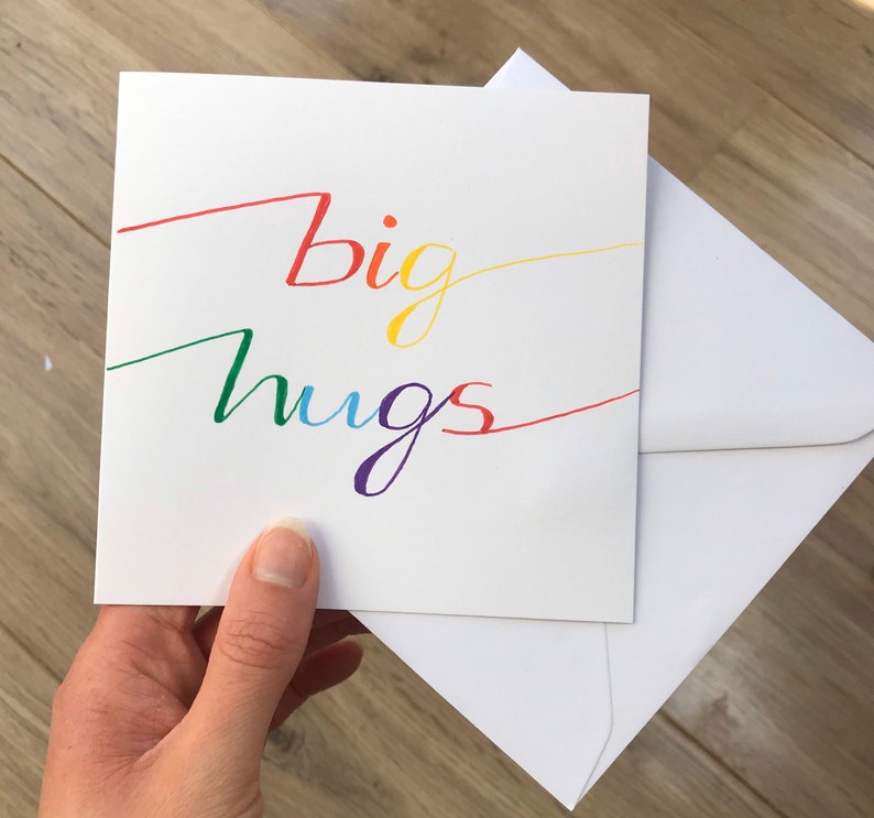 May include: A white card with the words "big hugs" written in rainbow colors.