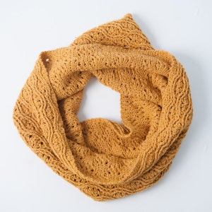 May include: A crocheted infinity scarf in a warm mustard yellow color. The scarf is made with a delicate stitch pattern and has a soft, cozy texture.