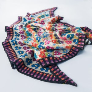 May include: A colourful knitted shawl with a geometric pattern and a black, purple and orange border.