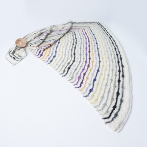 May include: A white crocheted shawl with multicoloured stripes in shades of purple, blue, yellow, and green. The shawl is folded and has a wooden button.