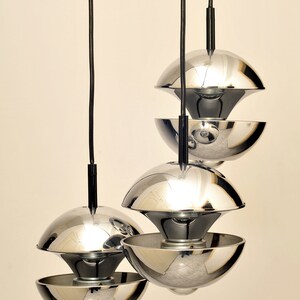 Peut inclure: Un ensemble de trois lampes suspendues en chrome au design unique. Chaque lampe est compos&eacute;e de deux demi-sph&egrave;res superpos&eacute;es, cr&eacute;ant un effet de superposition.