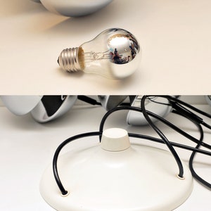 Peut inclure: Un luminaire de plafond blanc avec une finition chrom&eacute;e et une base blanche. La lampe a un cordon noir et une ampoule transparente.