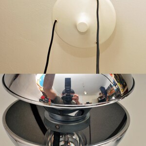Peut inclure: Un luminaire de plafond chrom&eacute; avec deux abat-jours en forme de bol. La lumi&egrave;re est suspendue au plafond par deux fils noirs.