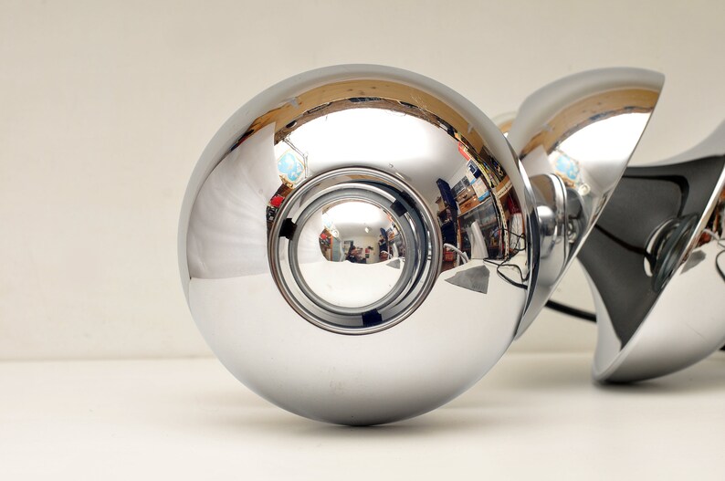 Peut inclure: Un ensemble de trois luminaires de plafond sph&eacute;riques chrom&eacute;s avec une surface r&eacute;fl&eacute;chissante. Les luminaires sont reli&eacute;s par un fil noir.
