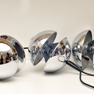 Peut inclure: Un ensemble de quatre lampes pendantes sph&eacute;riques chrom&eacute;es avec des cordons noirs. Les lampes sont con&ccedil;ues pour &ecirc;tre r&eacute;glables, chaque sph&egrave;re pouvant pivoter et s'incliner.