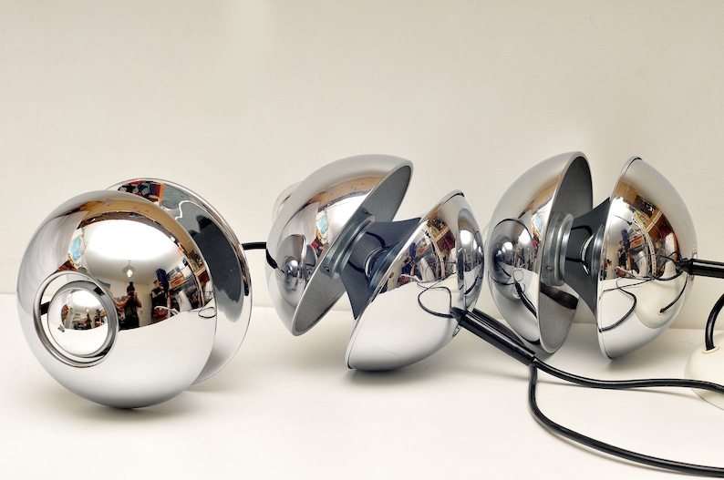 Peut inclure: Un ensemble de quatre lampes pendantes sph&eacute;riques chrom&eacute;es avec des cordons noirs. Les lampes sont con&ccedil;ues pour &ecirc;tre r&eacute;glables, chaque sph&egrave;re pouvant pivoter et s'incliner.