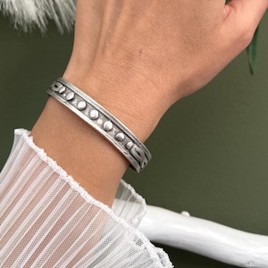 Pulsera unisex ajustable con puntos grabados en plata antigua y abierta.