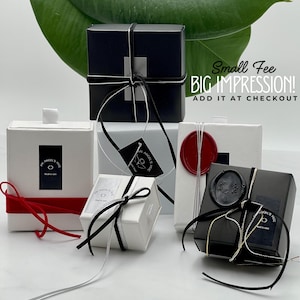 a collection of small gift boxes with black and white ribbons, placed on a white surface.