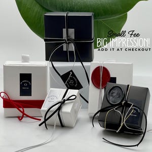 a collection of small gift boxes with black and white ribbons, placed on a white surface.