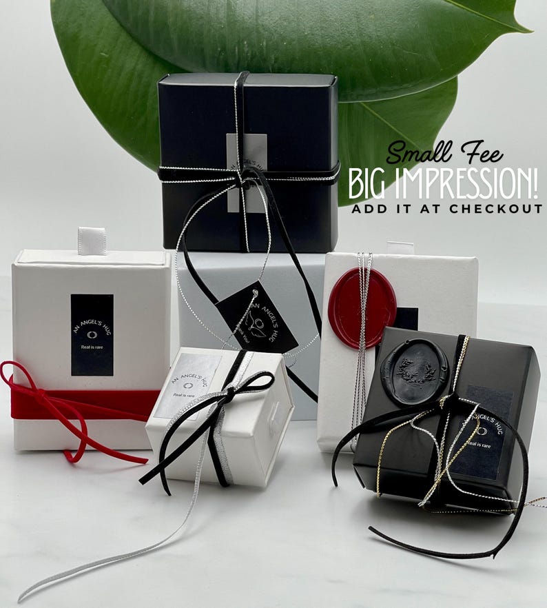 a collection of small gift boxes with black and white ribbons, placed on a white surface.